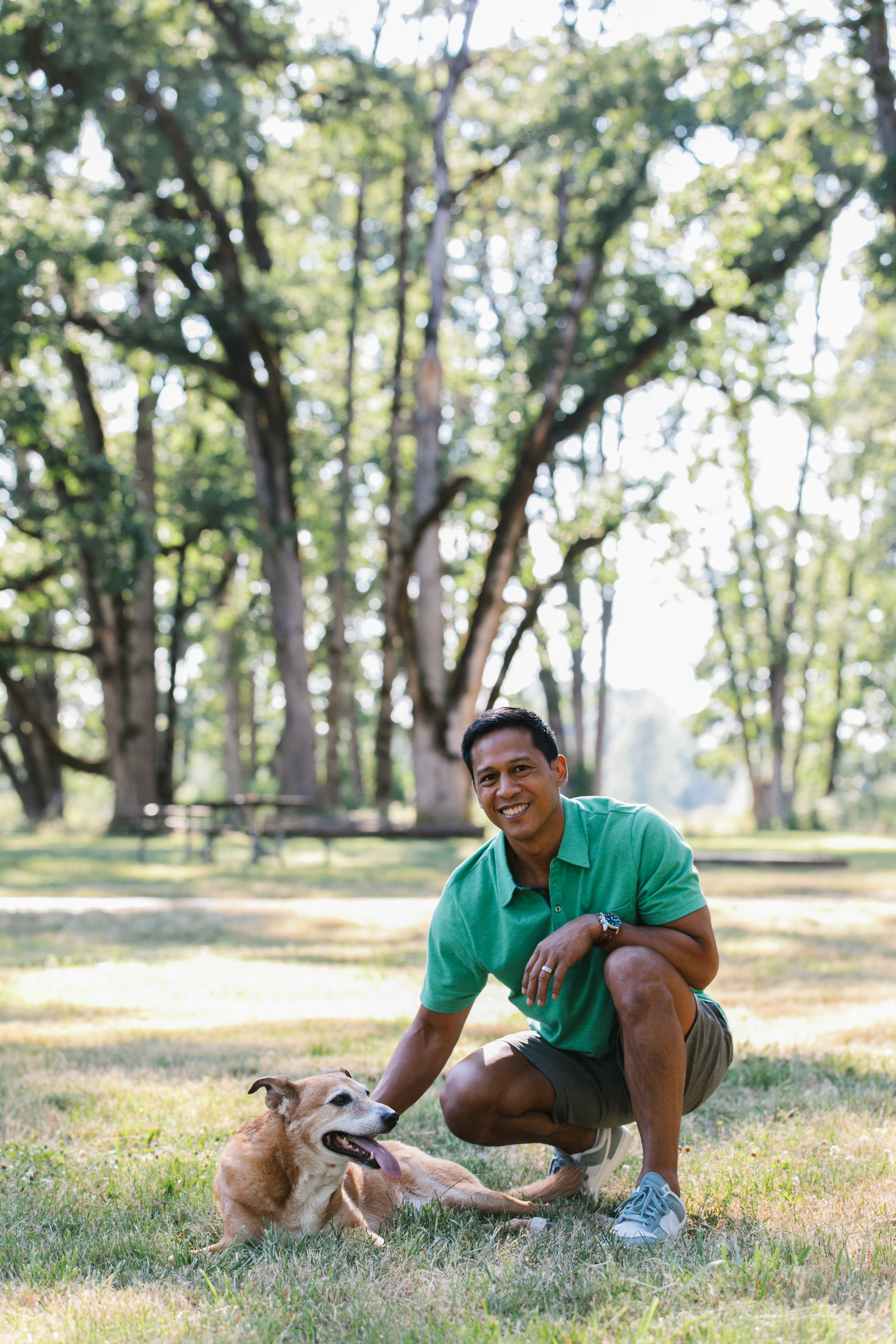 Kevin Perlas crouched down with his dog in a park