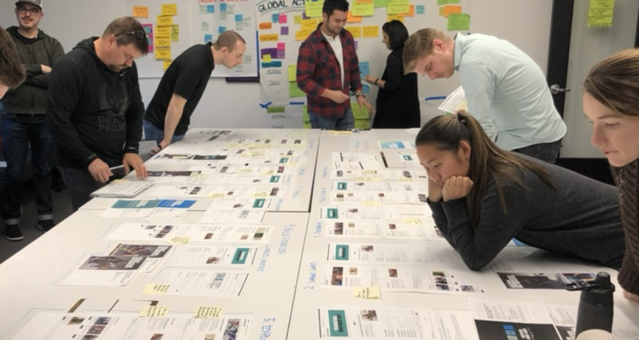 Team reviewing printed research artifacts spread across a conference table
